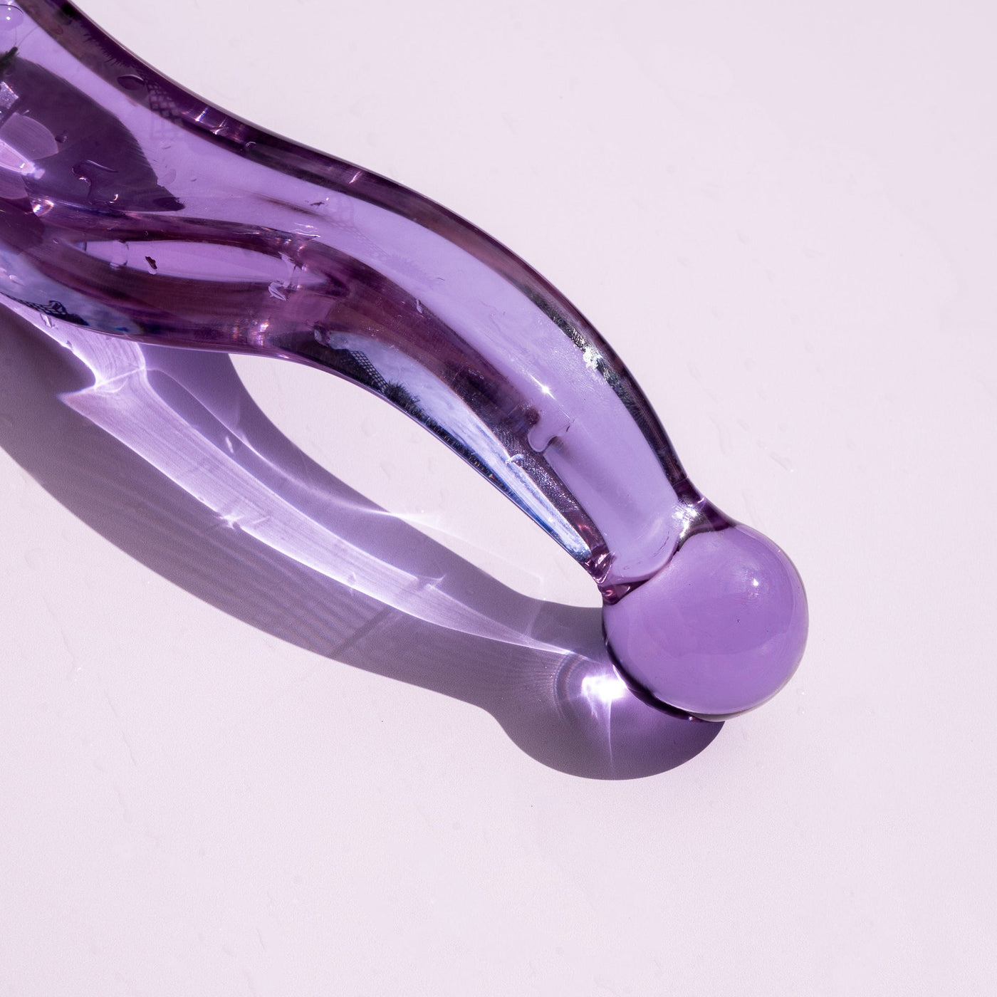 Pussy paddle thick curved pleasure wand in lilac. Pictured on pale purple background.